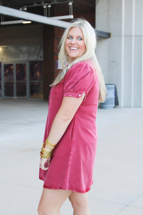 Woman with blonde hair wearing a short-sleeve maroon denim midi dress.