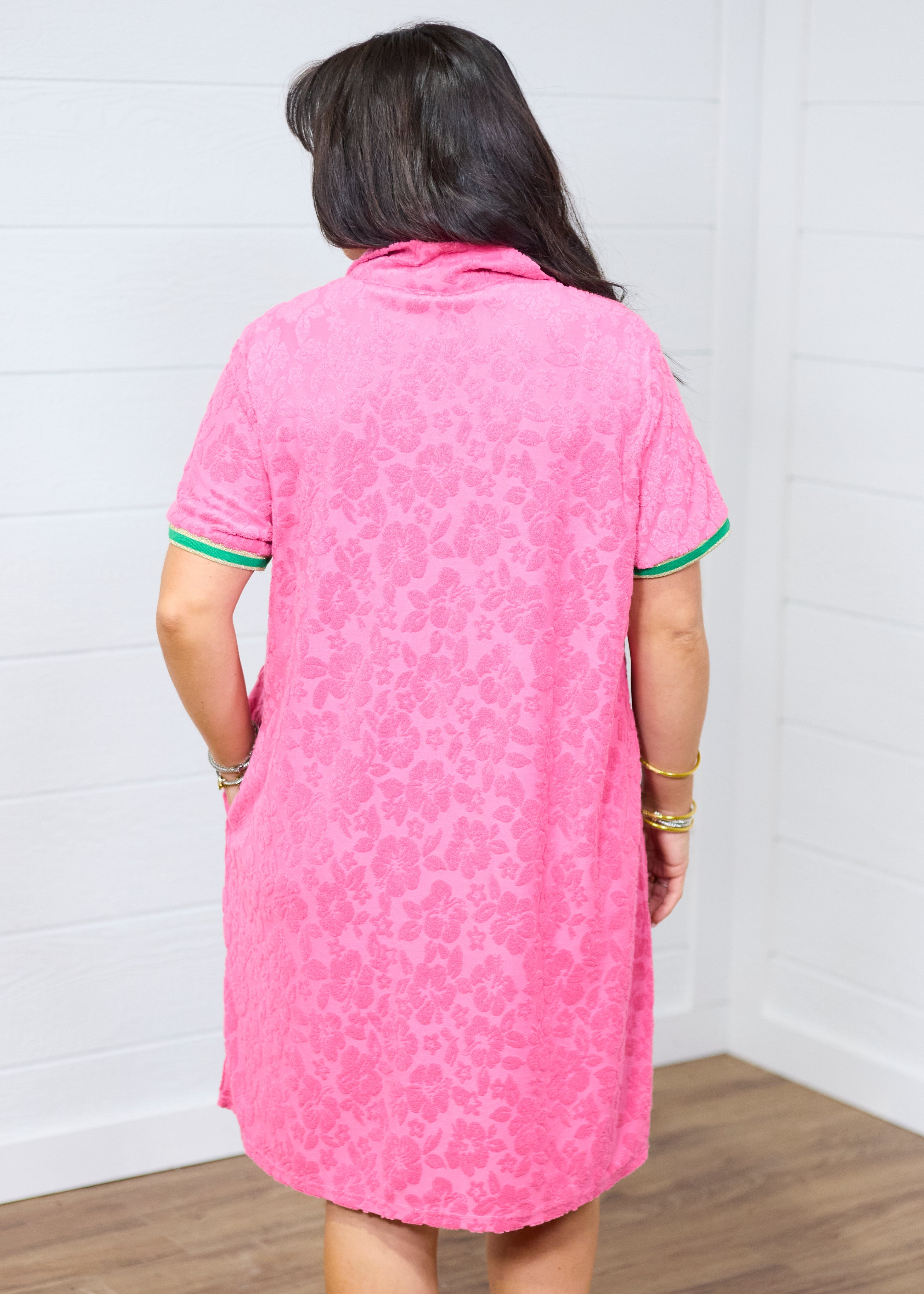 Woman with dark hair standing in a back profile position wearing the Cami Dress against a white background. The focal point of this image is the leopard fabric in pink as well as striping along cuff.