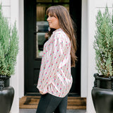 Woman with dark hair wearing a long-sleeve silky top with nutcracker graphics. Model paired this top with faux leather leggings.
