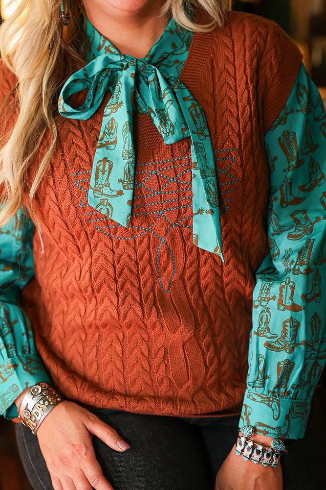 Woman with blonde hair standing in a front profile position wearing the Kodi Vest in a lifestyle scene. The focal point of this image is v-neckline and turquoise boot stitch. the model paired this top with dark-wash denim jeans.