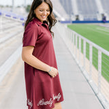Woman with dark hair wearing a midi maroon dress with howdy embroidery.