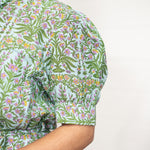 Woman with dark hair standing in a front profile position wearing the Amelia Dress against a white background. The focal point of this image is the floral detail in the sleeve, and detail on cuff. 