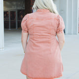 Woman with blonde hair wearing short-sleeve burnt orange midi dress. 