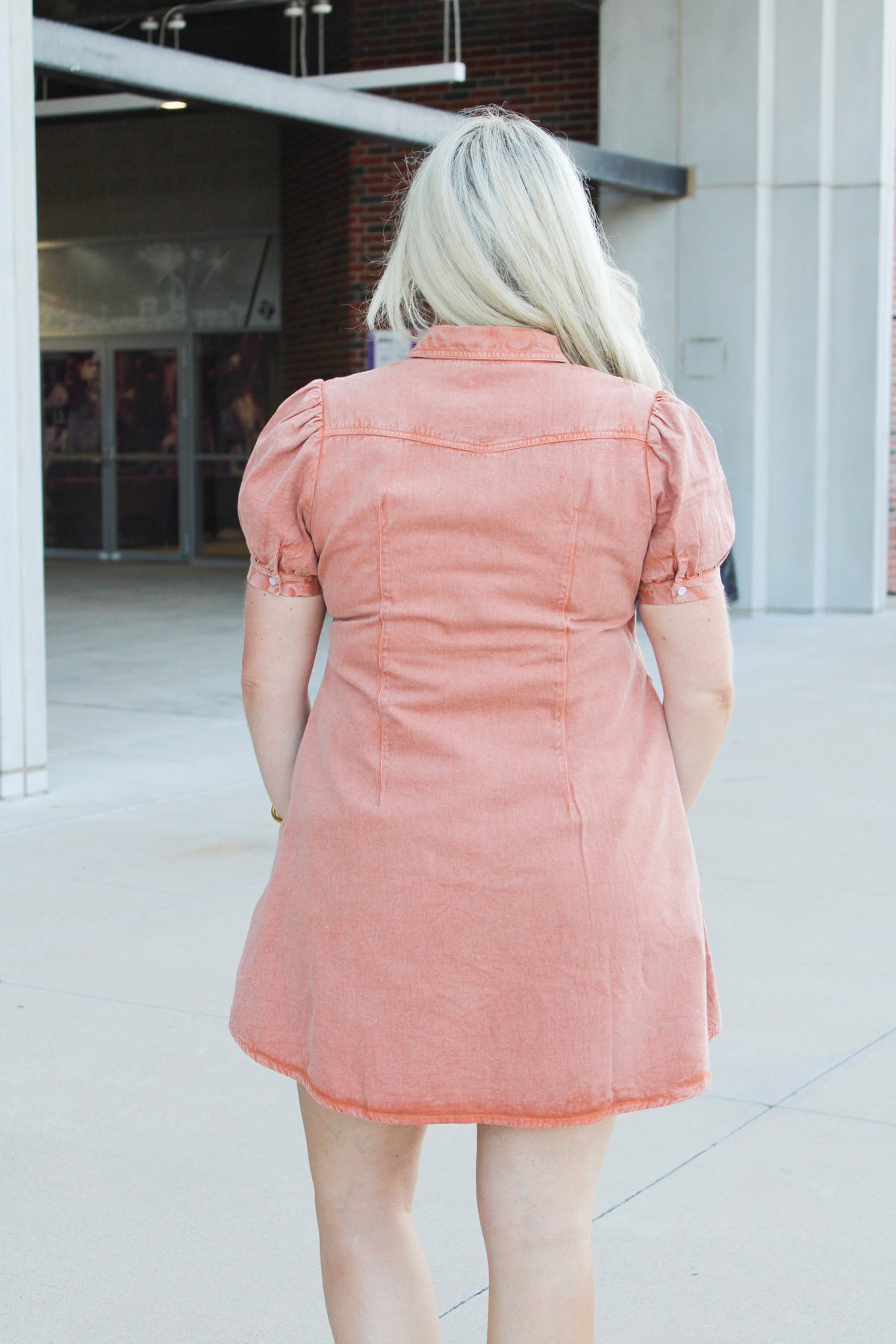 Woman with blonde hair wearing short-sleeve burnt orange midi dress. 