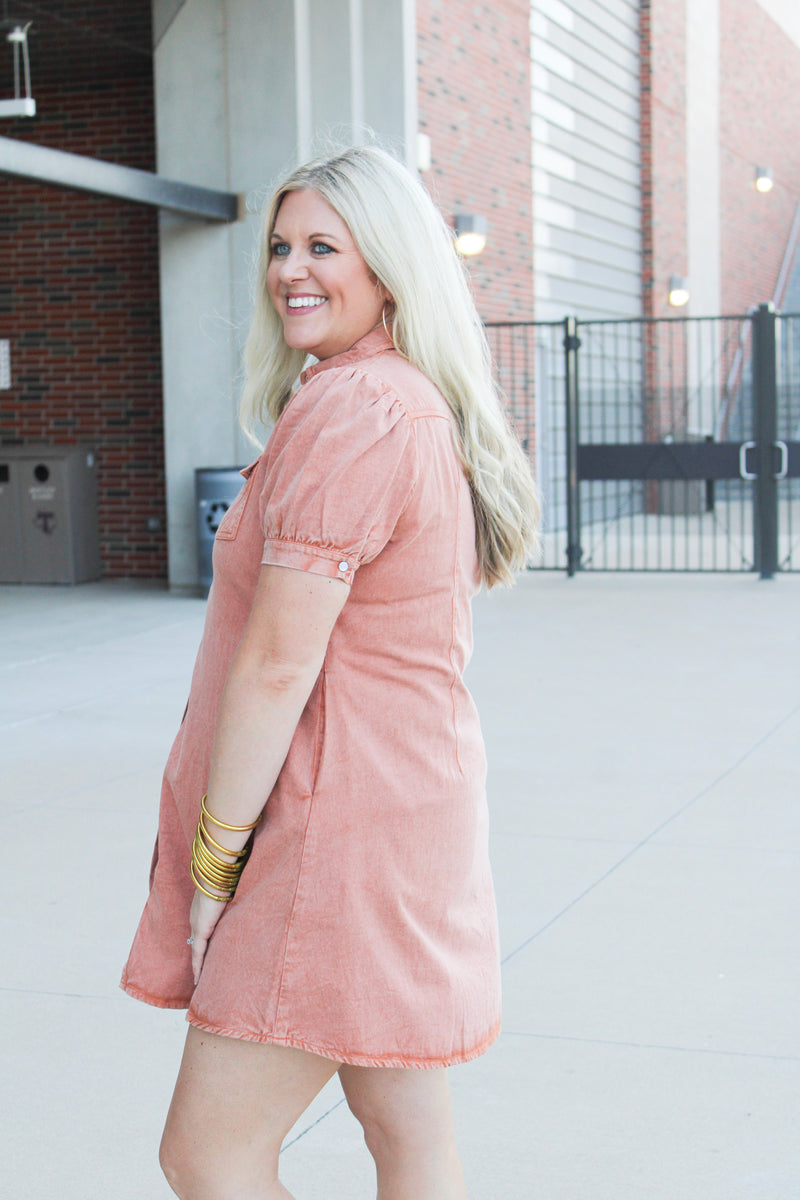 Woman with blonde hair wearing  a burnt orange midi dress.