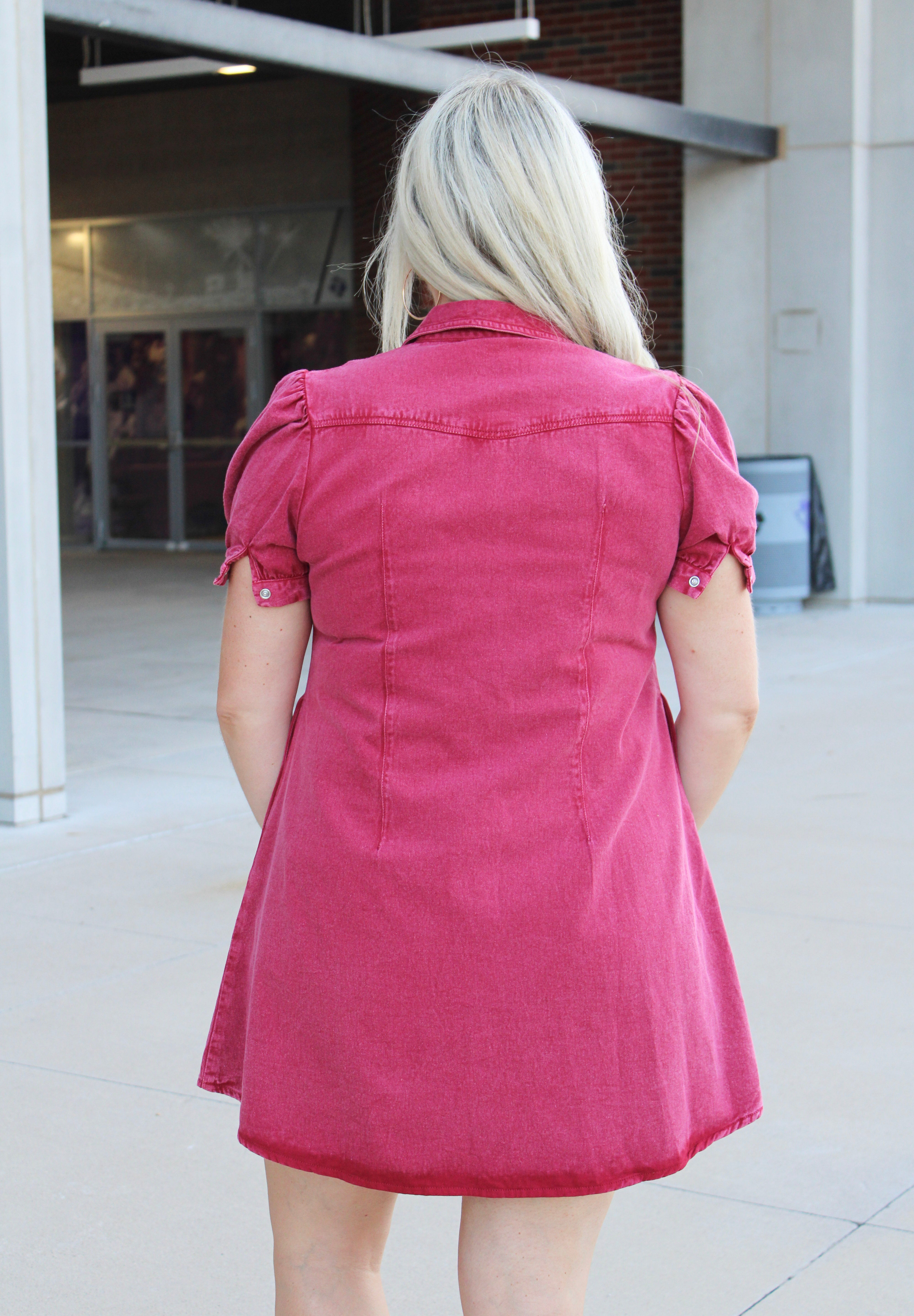 Woman with blonde hair wearing a maroon denim dress.