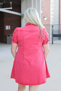Woman with blonde hair standing in a back profile position wearing a midi red denim dress.
