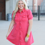 Woman with blonde hair standing in a front profile position wearing a midi red denim dress. 