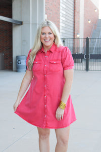 Woman with blonde hair standing in a front profile position wearing a midi red denim dress. 