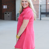Woman with blonde hair standing in a side profile position wearing a midi red denim dress. 