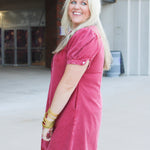 Woman with blonde hair wearing a short-sleeve maroon denim midi dress.