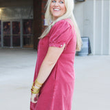 Woman with blonde hair wearing a short-sleeve maroon denim midi dress.