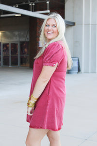 Woman with blonde hair wearing a short-sleeve maroon denim midi dress.