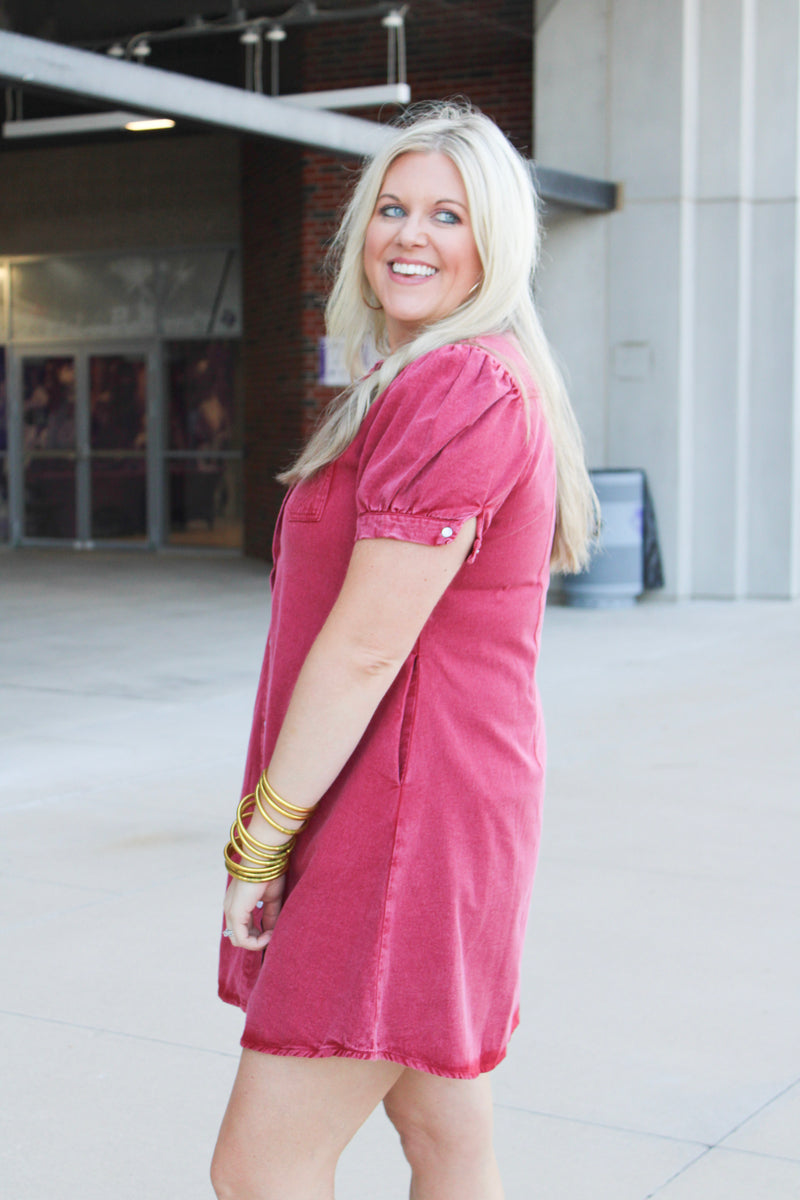 Woman with blonde hair wearing a short-sleeve maroon denim midi dress.
