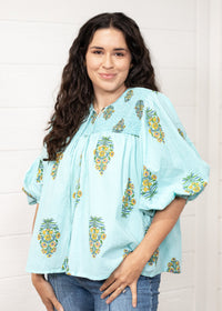 Woman with dark hair standing in a front profile position wearing the Ava Top against a white background. The focal point of this image is to see all aspects of the top. The model paired this top with dark-wash denim jeans. 