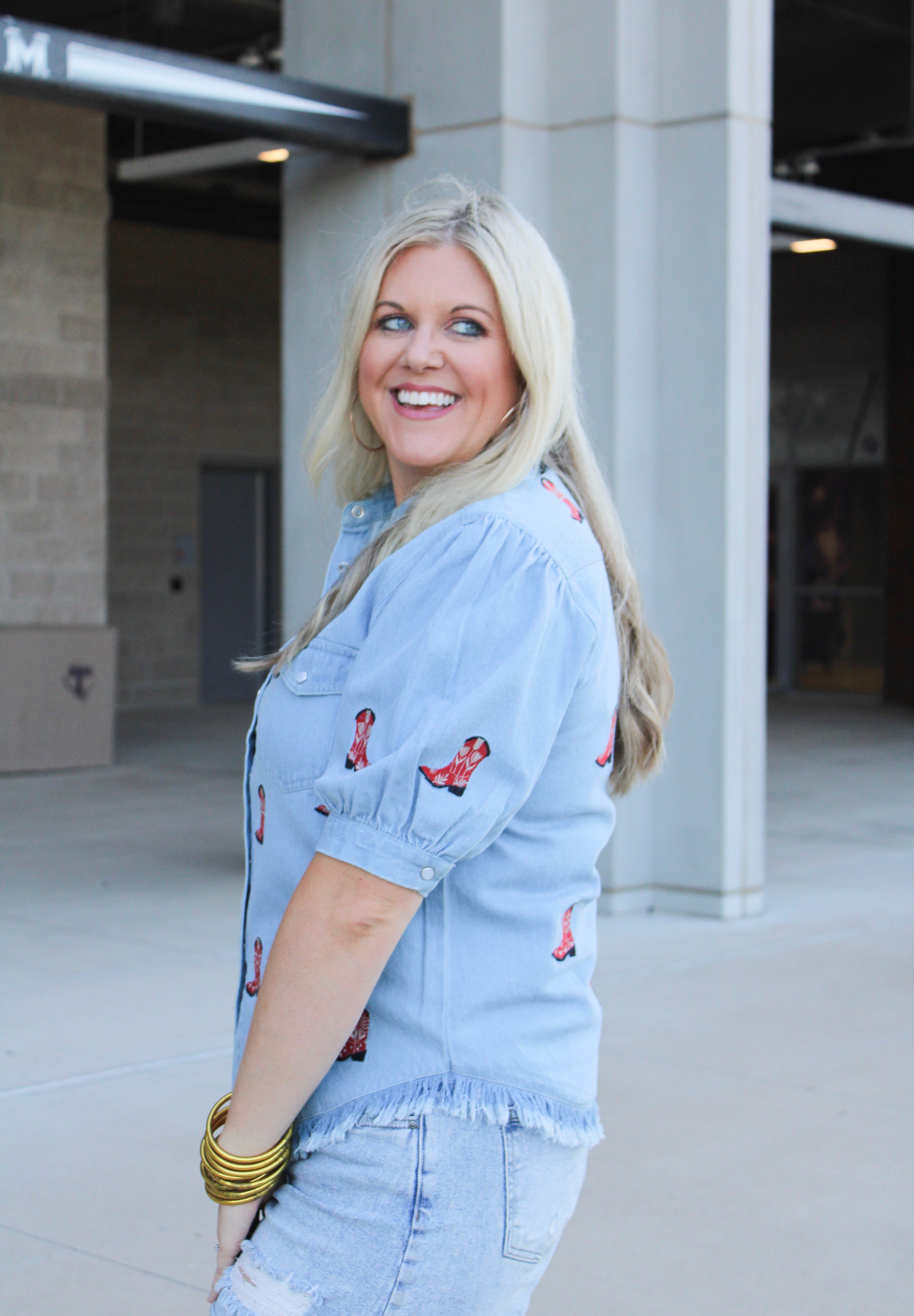 Woman with blonde hair wearing a short-sleeve denim shirts with red embroidered boots. The model paired this top with light-wash denim jeans. 