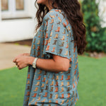 Woman with dark hair standing in a side profile position wearing the Basic Tee in a lifestyle scene. The model paired this top with light-wash denim jeans.