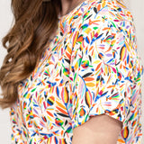 Woman with dark hair standing in a side profile position wearing the Basic Tee against a white background. The focal point of this image is a deep focal length into the graphics on top. 