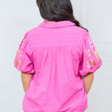 Woman with dark hair standing against a white background wearing the Brinley top. The model is in a back profile position, and paired top with light-wash jeans. 