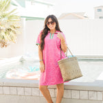 Woman with dark hair standing in front profile position wearing the Cami Dress in a lifestyle scene. The focal point of this image is the dress in its entirety. The model paired this dress with a woven beach bag and transparent sandals with rhinestones. 
