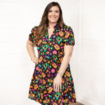 Woman with dark hair wearing the Claire Dress against a white background. The focal point of the image is the front graphics of the dress and slight emphasis on neckline and belt. 