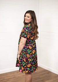 Woman with dark hair standing against a white background wearing the Claire Dress in a side profile position. The focal point of this image is the graphics on side of dress and slight emphasis on puffy sleeves. 