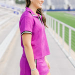 Woman with dark hair standing in a side profile position wearing the Daisy Top & Jade skirt in a lifestyle scene. The focal point of this image is the striping on the cuff of shirt and side of skirt as well as length of both top and skirt. 