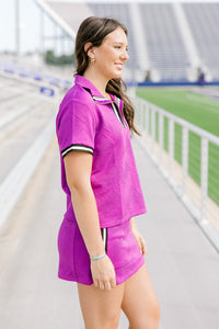 Woman with dark hair standing in a side profile position wearing the Daisy Top & Jade skirt in a lifestyle scene. The focal point of this image is the striping on the cuff of shirt and side of skirt as well as length of both top and skirt. 