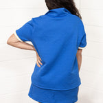 Woman with dark hair standing in a back profile position wearing the Daisy Top and Jane Bottoms set against a white background. The focal point of this image is the detailed grooves on the back of the top and bottoms. 