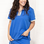 Woman with dark hair standing at a front profile wearing the Daisy Top and Jane Skirt set against a white background. The focal point for this image is the entirety of the set. 