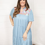 Woman with dark hair standing in a front profile position wearing the Evie Dress against a white background. The focal point of this image is the dresses entirety.
