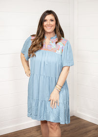 Woman with dark hair standing in a front profile position wearing the Evie Dress against a white background. The focal point of this image is the dresses entirety.