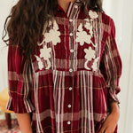 Woman with dark hair standing in a front profile position wearing the Faye Top against a white background. The focal point of this image is the pleating on front of top as well as the buttons and white floral embroidery on chest. The model paired this top with light-wash denim jeans. 
