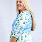 Woman with blonde hair standing in a side profile position wearing the Helen Dress against a white background. The focal point for this image is the up-close view of embroidery on quarter sleeve and pleated cuff. 