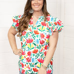 Woman with dark hair standing in a front profile position wearing the Iris Top against a white background. The focal point of this image is the top in its entirety. The model paired this top with dark-wash denim shorts.