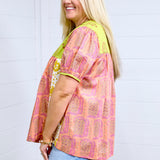 Woman with blonde hair showing side profile at a farther angle in Jeanie Top. Showing more range in picture, paired with denim skirt. 