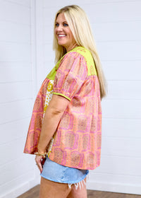 Woman with blonde hair showing side profile at a farther angle in Jeanie Top. Showing more range in picture, paired with denim skirt. 