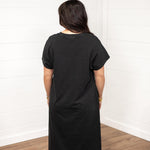 Woman with dark hair in a back facing position wearing the Jo Dress against a white background. The focal point of this image is the back of the dress with emphasis on it's length and color. 