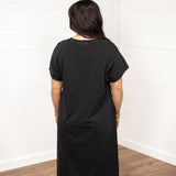 Woman with dark hair in a back facing position wearing the Jo Dress against a white background. The focal point of this image is the back of the dress with emphasis on it's length and color. 