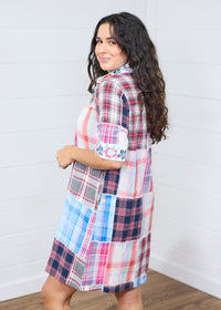 Woman with dark hair standing in a side profile position wearing the Paisley Tunic against a white background. The focal point of this image is the length of dress and embroidery on the sleeves. 
