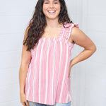 Woman with dark hair standing in a front profile position wearing the Sophia Top against a white background. The focal point for this image is the straight neckline. The model paired this top with light-wash denim jeans. 