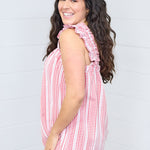 Woman with dark hair standing in a side profile position wearing the Sophia Top against a white background. The focal point for this image is the sleeve ruffles, gingham graphic, and length of top. The model paired this top with light-wash denim jeans.