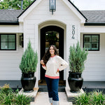 Woman with dark hair wearing a sweatshirt with red & white striping along cuff and collar. On the back of top there is a multi color bible verse. Model paired this top with dark-wash denim jeans. 