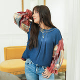 Woman with dark hair standing in a front profile position wearing the Tammy Top in a lifestyle scene. The focal point of this image is the waffle knit fabric and puffy sleeves. The model paired this top with mid-wash denim jeans. 