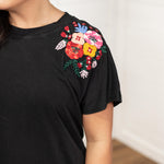 Woman with dark hair in a front facing position wearing the Jo Dress with a deep focal length. The focal point of this image is the shoulder region with emphasis on the embroidery on the sleeves. 