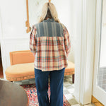Woman with blonde hair wearing a quarter sleeve top with plaid patch-work paired with dark-wash denim jeans. 