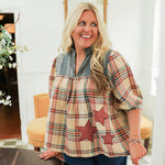 Woman with blonde hair wearing a quarter sleeve top with plaid patch-work paired with dark-wash denim jeans. 