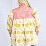 Woman with blonde hair showing back profile of the Tinley Top against a white background. This image shows the graphics on back of top, and is paired with light-wash denim shorts. 