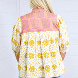 Woman with blonde hair showing back profile of the Tinley Top against a white background. This image shows the graphics on back of top, and is paired with light-wash denim shorts. 