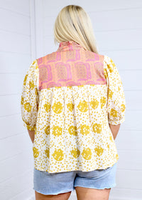 Woman with blonde hair showing back profile of the Tinley Top against a white background. This image shows the graphics on back of top, and is paired with light-wash denim shorts. 